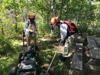 two trail maintance volunteers with mower and string trimmer